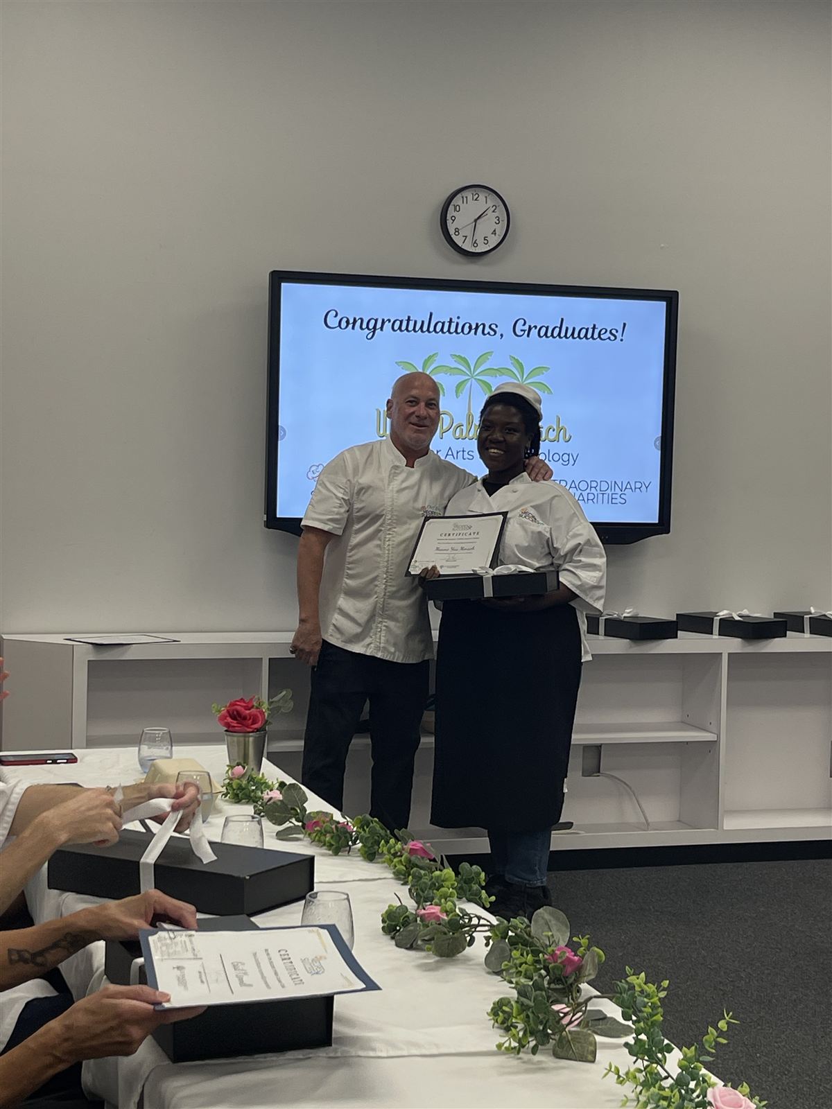 Graduate Maame Yaa Mensah receiving her certificate from a Recipes for Success chef at the WPBCAT graduation